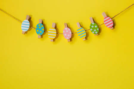 A garland of colorful Easter eggs on a yellow background. The concept of the holiday is Easter, Christ is resurrected. Banner. A place for textの写真素材