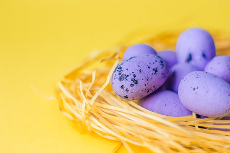 Purple Easter eggs lie in the nest on a yellow background close up. The concept of the holiday is Easter, Christ is resurrected. Banner. A place for text. Mock up. View from above. Selective focus.の写真素材