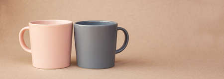Two cups pink and gray color for coffee, stand on a beige background. A place for text. banner. Coffee day. Valentine's Day. Close-up cups. Minimalism with coffee. Breakfastの写真素材