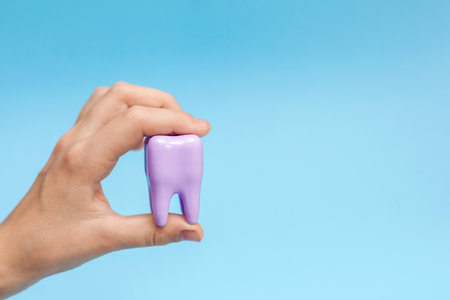 A hand holding a big tooth on a blue background. Concept of dental care. Teeth Clean and Oral Health. Close-up. Place for textの写真素材