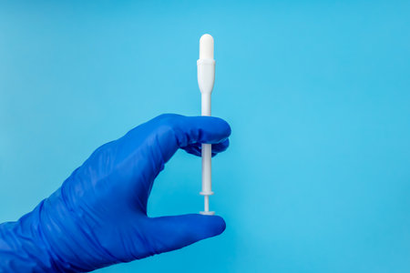 Tablet and applicator in hand on blue background. Close up. Place for text. Caring for women's healthの写真素材