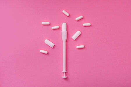 Vaginal suppositories with pills on a pink background. Caring for women's health. Close up of the product. Flat styling. Place for text.の写真素材
