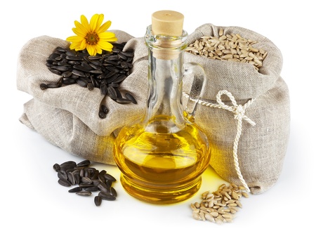 Macro view of purified and raw sunflower seeds in flax sacks and glass bottle of sunflower oil isolated on white backgroundの写真素材
