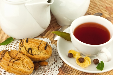 Cup of tea on plate, cakes and leaves on the matの写真素材