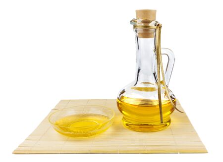 Glass bottle of oil and saucer with oil on the mat isolated on white backgroundの写真素材