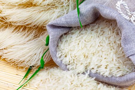 Macro view of sack with white rice and rice vermicelli with greens on the matの写真素材