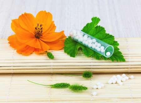 Homeopathic medication on the leaf with flower on the matの写真素材