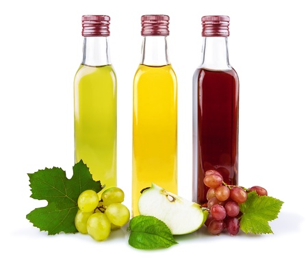 Glass bottles of three kind of vinegar with fruit and leaves isolated on white backgroundの写真素材