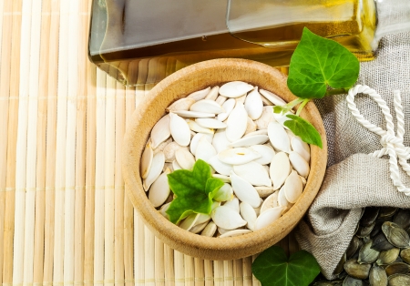 Composition from pumpkin seeds and pumpkin oil with green leaves on the matの写真素材