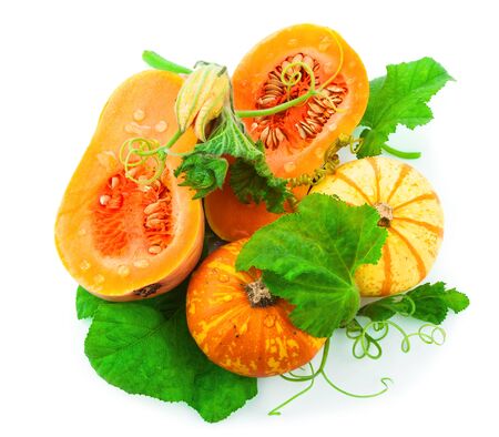 Cut pumpkin with pumpkin seeds and green leaves isolated on white backgroundの写真素材