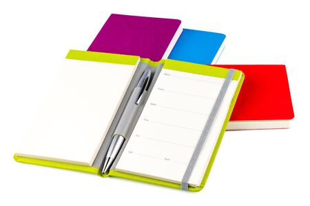 Colourful notebooks with open notebook and ballpoint pen isolated on white backgroundの写真素材