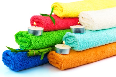 Towels of different colors with candles and bamboo on whiteの写真素材