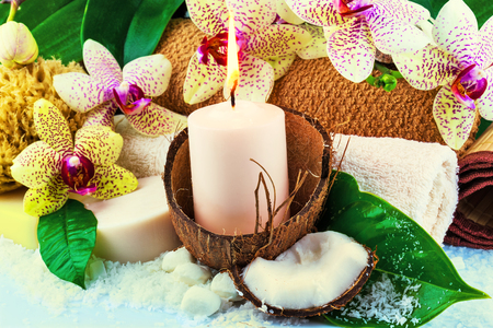 Spa concept with candle, coconut, orchid, towels, soap, green leavesの写真素材