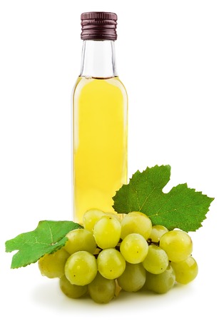 Glass bottle of green wine vinegar with a bunch of grapes isolated on white の写真素材