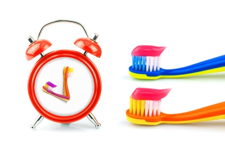 Composition from red clock, toothbrushes with pink toothpaste isolated on white backgroundの写真素材