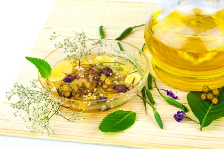 Glass saucer and carafe with oil and herbage with green leaves on the matの写真素材