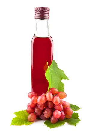 Glass bottle of red wine vinegar with a bunch of grapes and leaves isolated on white backgroundの写真素材