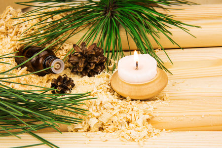 Macro view of candle, cones, glass bottle of oil, wooden sawdust, green pine twigs and logsの写真素材