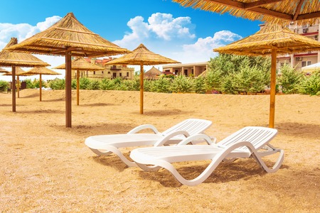 Sun beds and umbrellas on sand of beach near the hotelの写真素材
