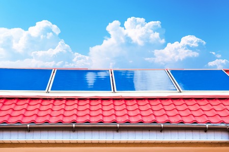 Solar panels on the roof with blue sky and cloudsの写真素材