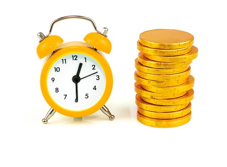 Clock with coins, time is money isolated on white backgroundの写真素材