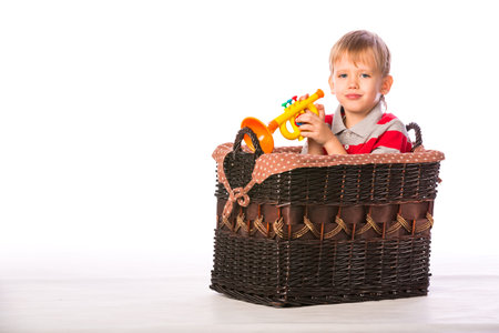 Boy with toy in basket on the floor isolated on white backgroundの写真素材
