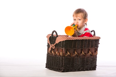 Boy with toy in basket on the floor isolated on white backgroundの写真素材