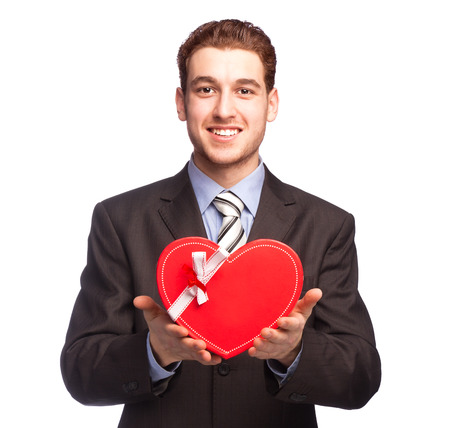 Businessman giving a heart-shaped red gift isolated on white backgroundの写真素材