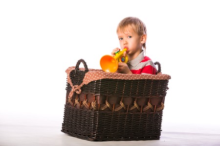 Boy with toy in basket on the floor isolated on white backgroundの写真素材