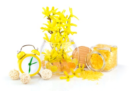 Composition from spring yellow flowers, aroma salt and alarm clock isolated on white backgroundの写真素材