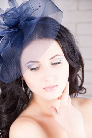 Dreamy girl with blue eyes looking down in blue hatの写真素材