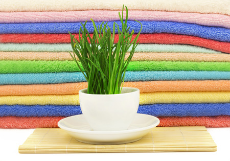 Spa concept with fresh grass with drops in the cup on the mat and multicolor towelsの写真素材