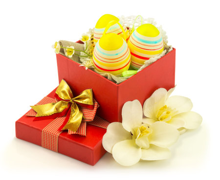Decorative easter eggs in opened red box with flowers isolated on white background