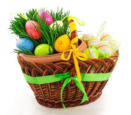 Macro view of wicker wooden basket with Easter eggs, fresh grass and color ribbons isolated on white backgroundの写真素材