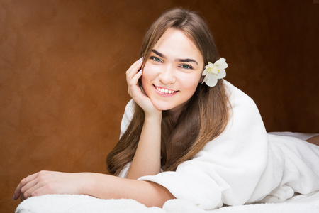 Smiling attractive young brunette woman in a white robeの写真素材