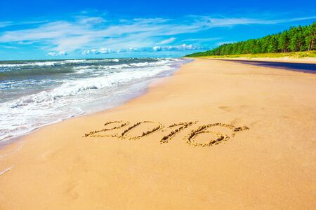 Romantic coastline with number 2016 on sand, backgroundの写真素材