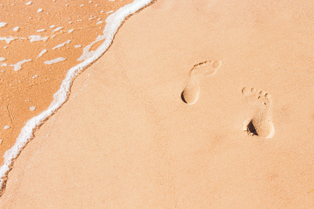 Abstract sand background with tracks of feet and sea waterの写真素材