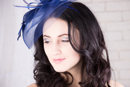 Dreamy girl with blue eyes looking down in blue hatの写真素材