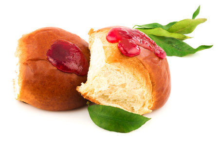 Fresh baked tasty sweet brioches, buns, loaves, bread with tasty berries jam and green leaves isolated on white backgroundの写真素材