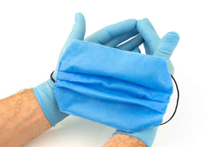 Male hands with blue rubber gloves and hold medical mask on white backgroundの写真素材