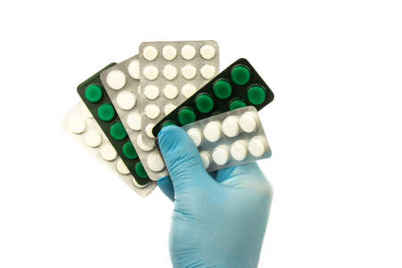 Male hand with blue rubber glove hold tablets in packaging on white backgroundの写真素材