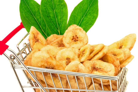 Macro view of banana chips with green leaves in metal trolley on white backgroundの写真素材