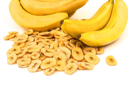 Macro view of heap of dried banana chips with yellow banana bunch on white backgroundの写真素材