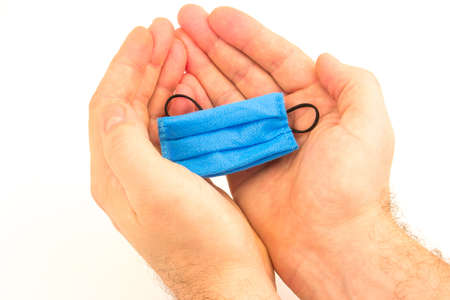 Coronavirus concept with male hands and blue personal protective medicine surgical equipment mask isolated on white background.の写真素材