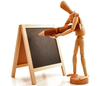 Concept with desk, board, blackboard, chalkboard, frame and wooden toy figure writing with pencil, pen. Isolated on white background.の写真素材
