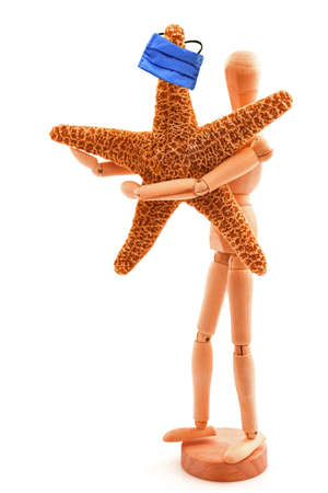 Coronavirus concept with wooden toy, sea star and blue protective medicine surgical equipment mask. Isolated on white background.の写真素材
