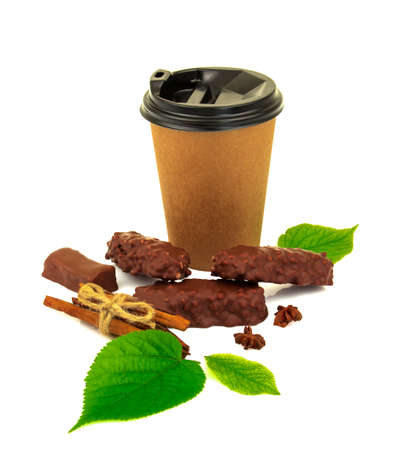 Paper glass with latte, cappuccino, chocolate candies, cinnamon, anise and fresh green leaves isolated on white backgroundの写真素材