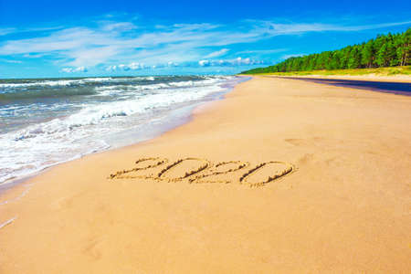 Romantic coastline with number 2020 on sand, backgroundの写真素材