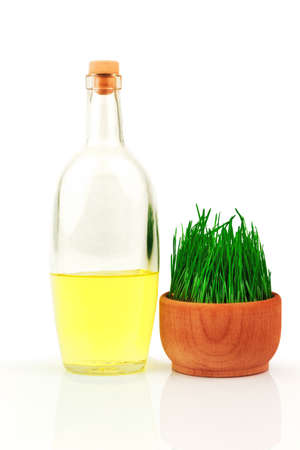 Glass transparent bottle and fresh sprouts of wheat in wooden bowl isolated on white backgroundの写真素材