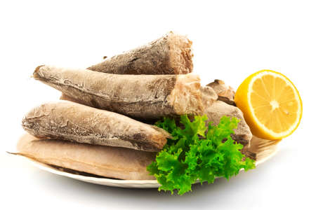 Macro view of frozen raw fish hake, pollock on the plate with lemon and leaves of salad lettuce isolated on white background.の写真素材